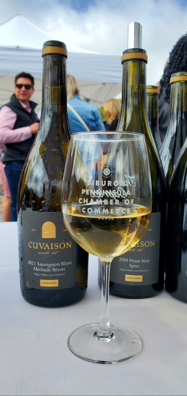 A glass of wine in front of two bottles of wine