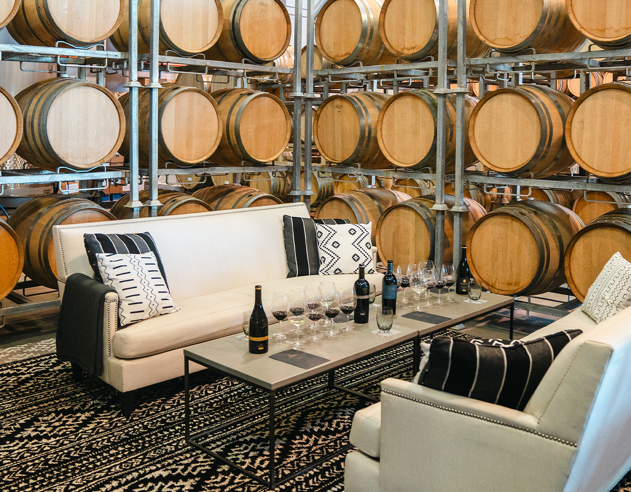 Indoor wine tasting with a table and wine glasses surrounded by wine barrels