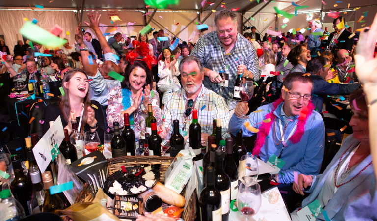 People at a wine auction celebrate under confetti