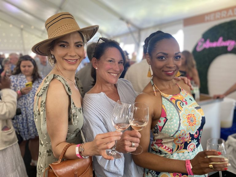 Three ladies holding wine glasses looking happy