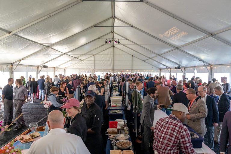 A tent full of people at a large wine tasting festival