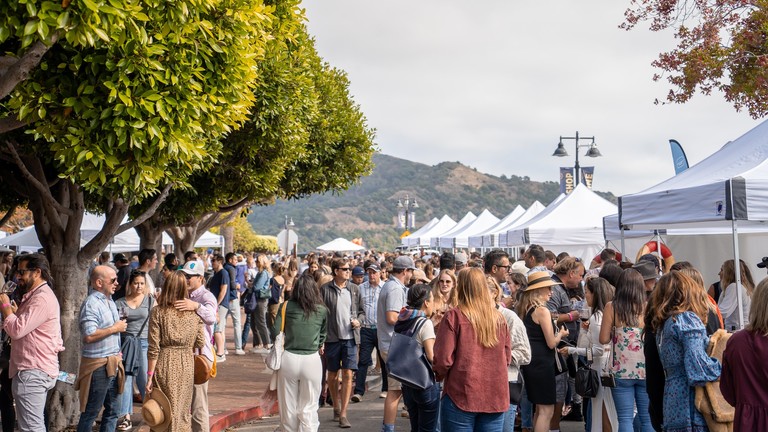 A crowd of people wander among tents at the Tiburon wine festival