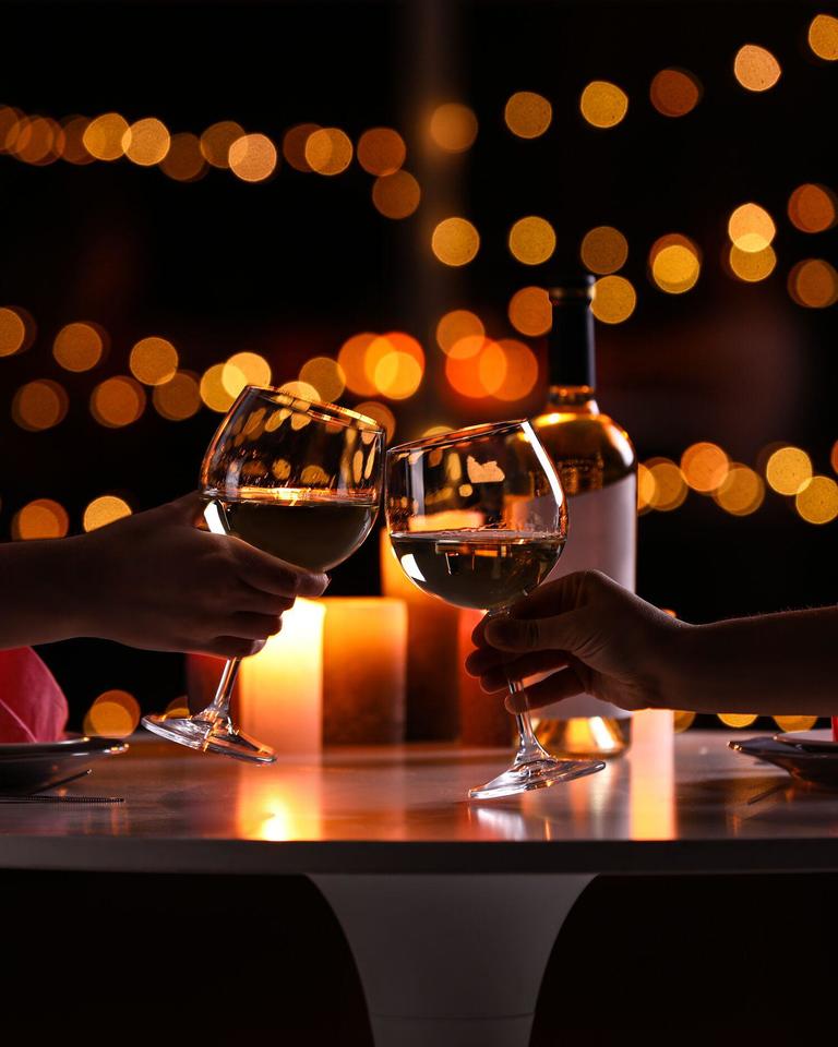 Two hands clink wine glasses