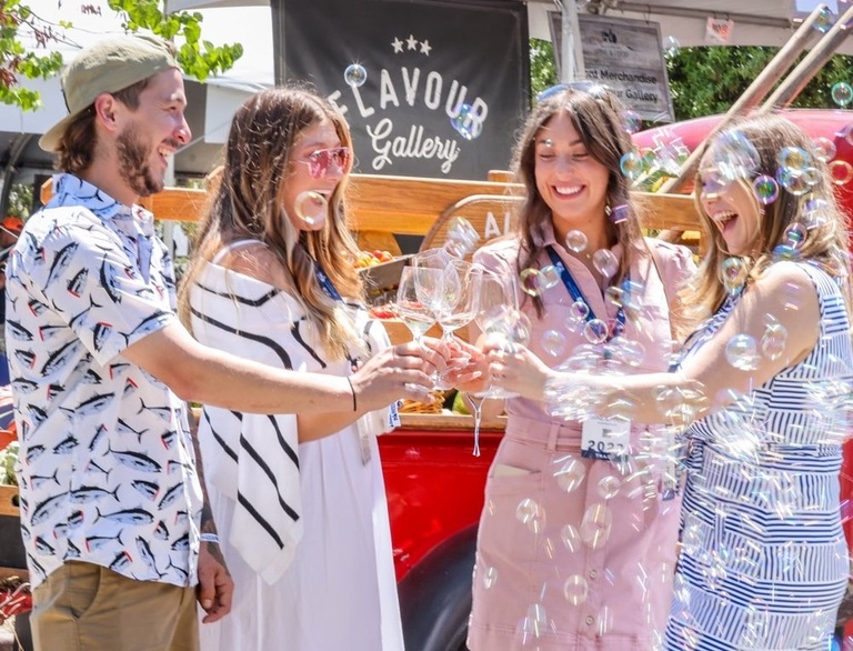 4 friends clink wine glasses while bubbles float in the air around them