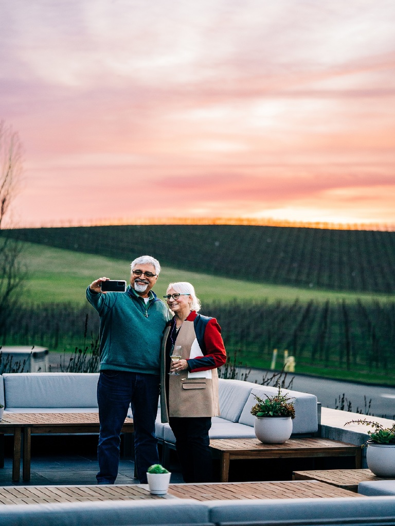 A couple takes a selfie before a colorfully pink sunset